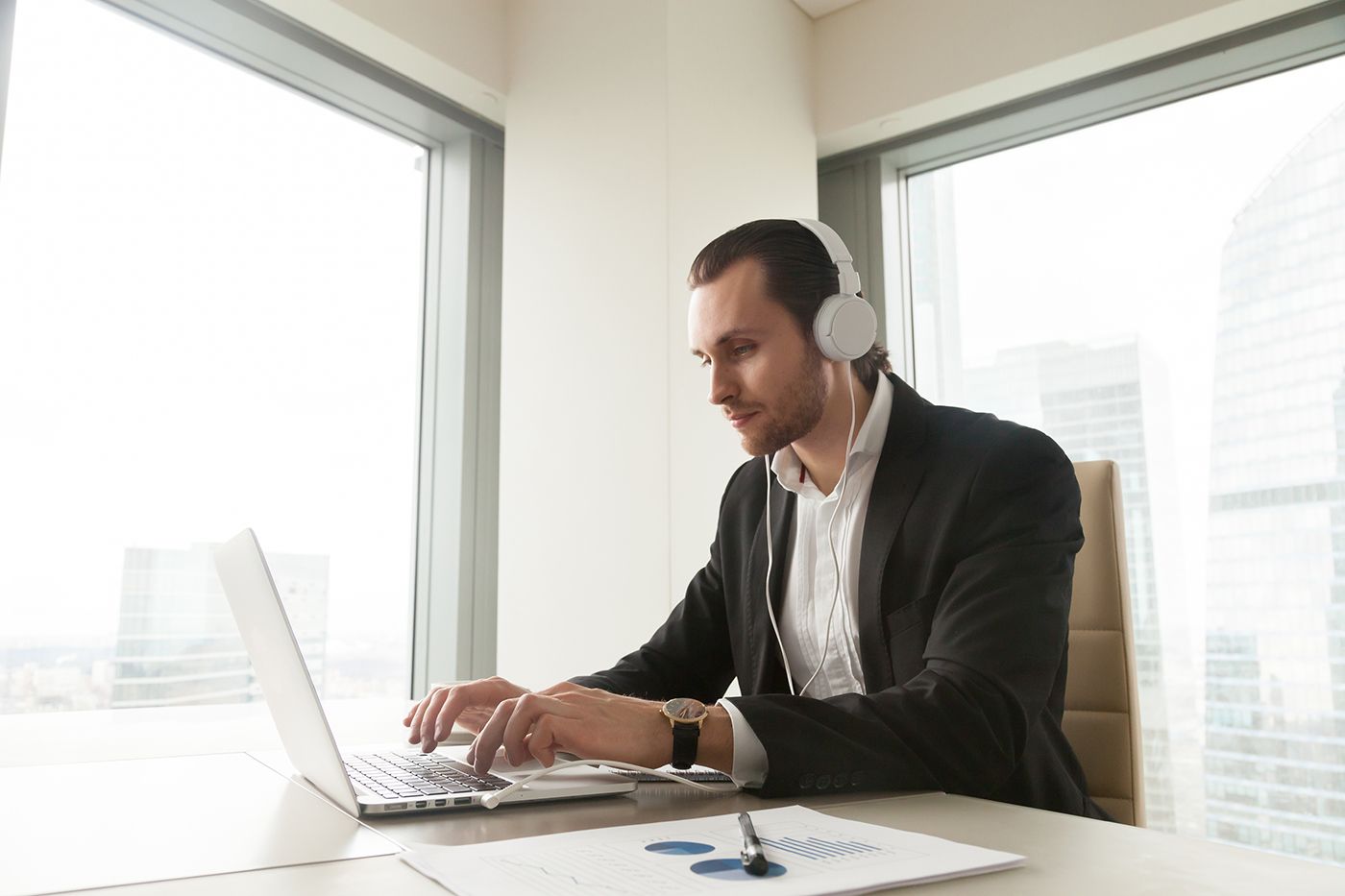 This man is following online meeting etiquette: Using headphones in a quiet, professional setting.